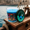 A Scurvy Dog 9-ounce tumbler jar, sitting on the deck of a pirate ship. Lid off. Front view.  Video game candle. Perfect gift for gamers. Premium soy wax scented candle.