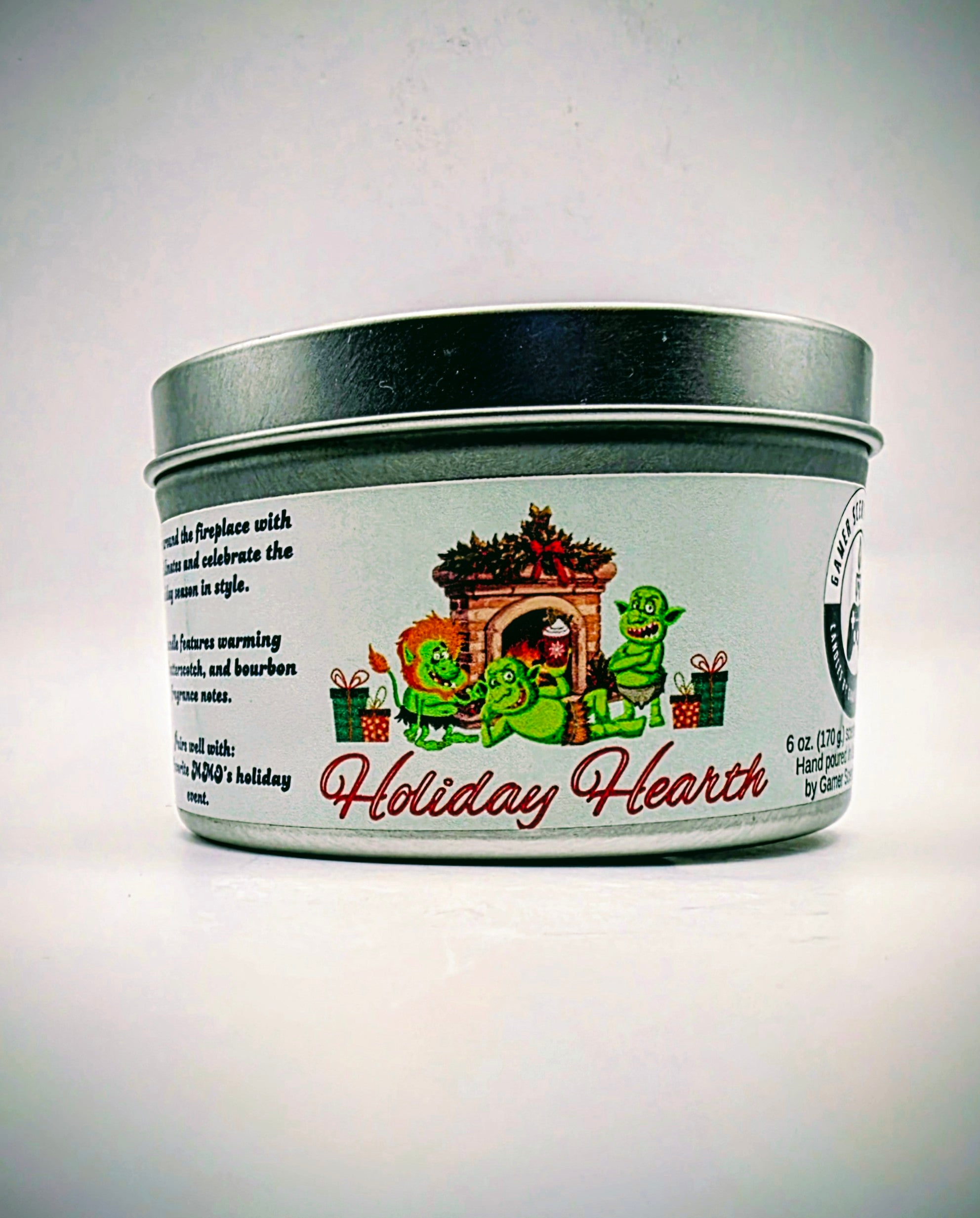 A 6 oz. candle in a candle tin named "Holiday Hearth" featuring a festive gathering of orcs around a fireplace during the holiday season.