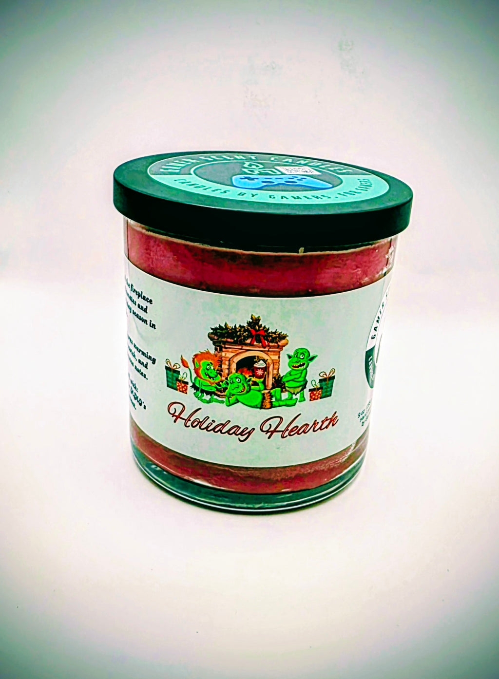 A 9 oz. candle in a glass tumbler jar named "Holiday Hearth". The label features a festive gathering of orcs around a fireplace during the holiday season.