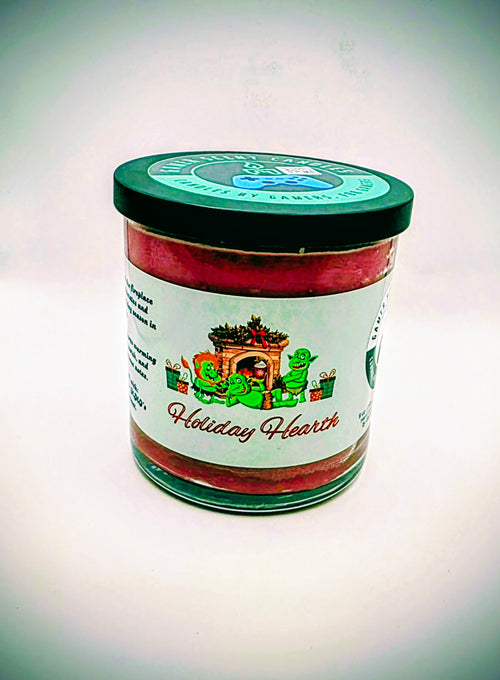 A 9 oz. candle in a glass tumbler jar named "Holiday Hearth". The label features a festive gathering of orcs around a fireplace during the holiday season.