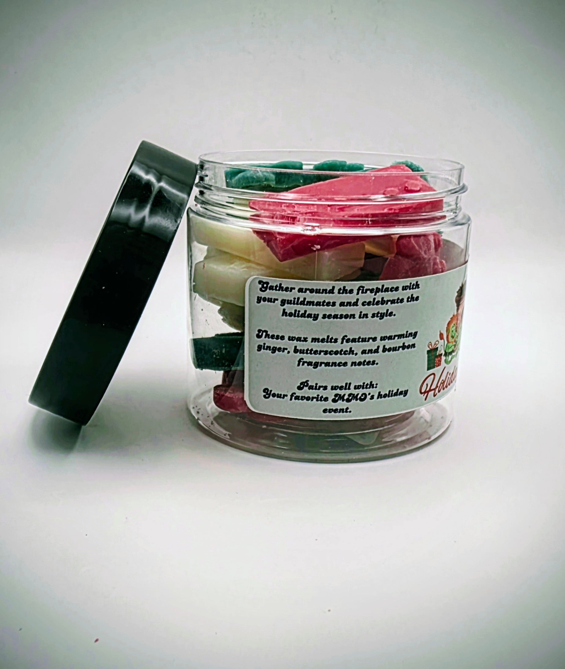 A jar of "Holiday Hearth" premium wax melts. The wax melts come in a clear plastic jar with a black lid, featuring a light-green label. The wax melts themselves come in an assortment of video game controller shapes and a mix of red, green, and white colors.