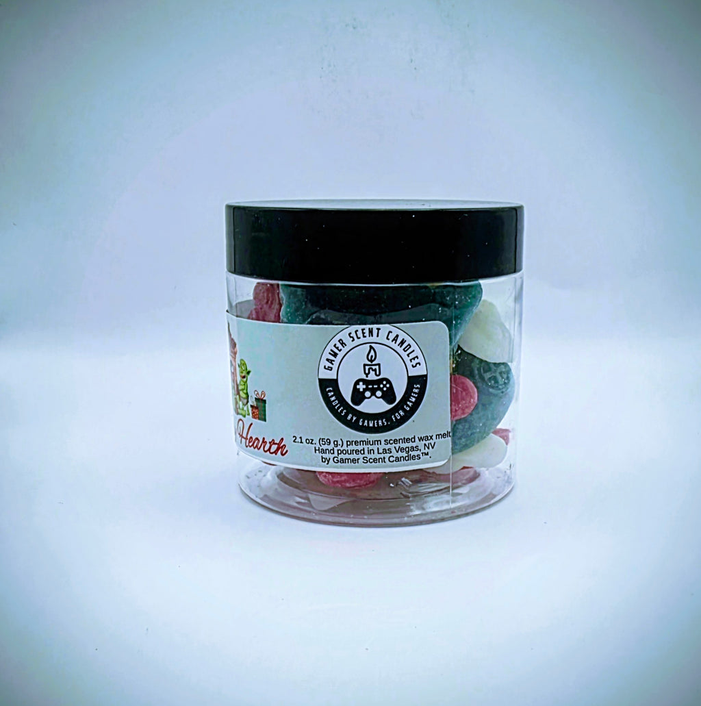 A jar of "Holiday Hearth" premium wax melts. The wax melts come in a clear plastic jar with a black lid, featuring a light-green label. The wax melts themselves come in an assortment of video game controller shapes and a mix of red, green, and white colors.