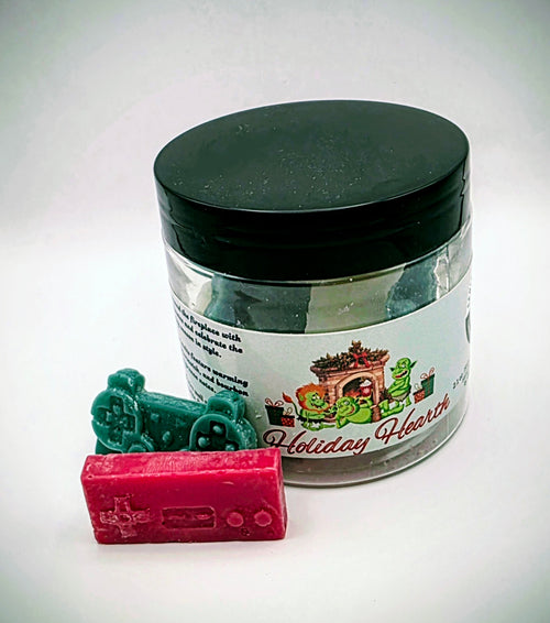 A jar of "Holiday Hearth" premium wax melts. The wax melts come in a clear plastic jar with a black lid, featuring a light-green label. The wax melts themselves come in an assortment of video game controller shapes and a mix of red, green, and white colors.