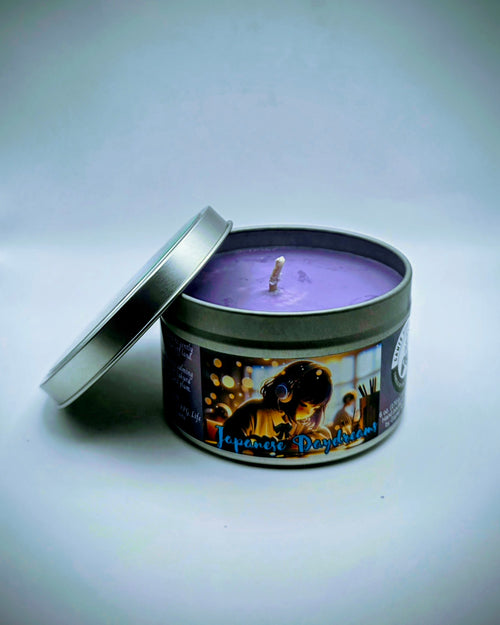Our "Japanese Daydreams" candle in a 6 oz. tin. The candle features Sakura (cherry blossom) and plum fragrance notes. The candle is purple and features a purple label with a young Japanese girl wearing headphones, daydreaming during class. Our 6 oz. candles have approximately a 25 hour burn time.