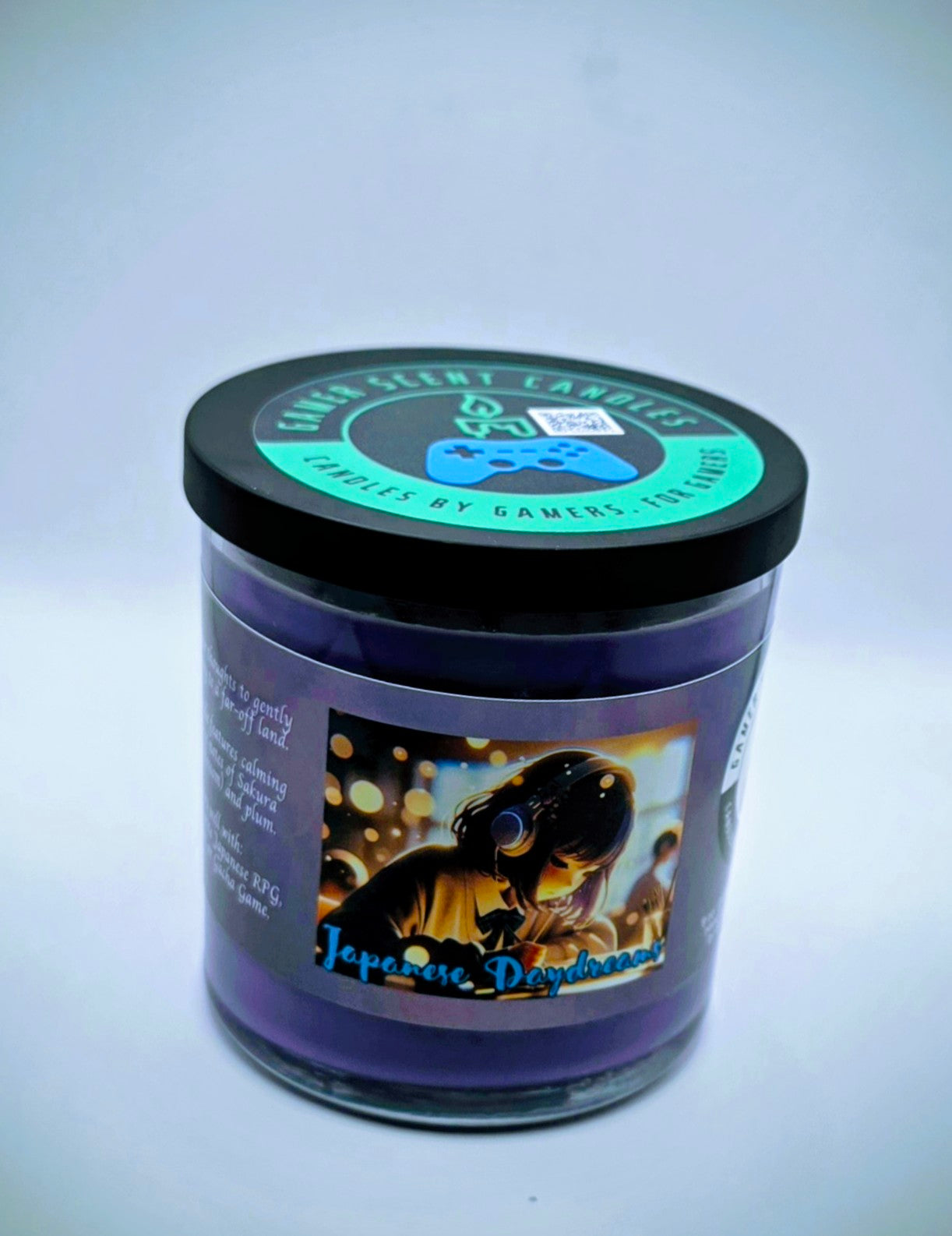 Our "Japanese Daydreams" candle in a 9 oz. glass tumbler jar. The candle features Sakura (cherry blossom) and plum fragrance notes. The candle is purple and features a purple label with a young Japanese girl wearing headphones, daydreaming during class. Our 9 oz. candles have approximately a 40 hour burn time.