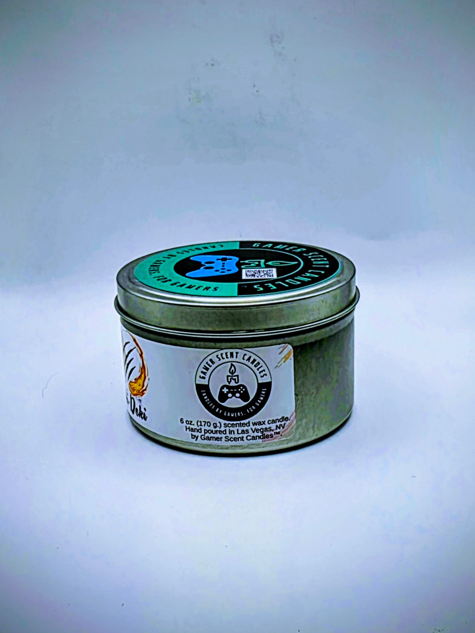 Our Oki-Doki candle in a candle tin. It has a net weight of 6 oz. and approximately a 25 hour burn time. It features a mixture of sweet and sour fragrance notes including peach, watermelon, and pink lemonade. The clash between sweet and sour is meant to represent the clash between powerful fighters in your favorite fighting game franchises. The label is white with images reminiscent of the fireball and slashing attacks featured in many fighting games.