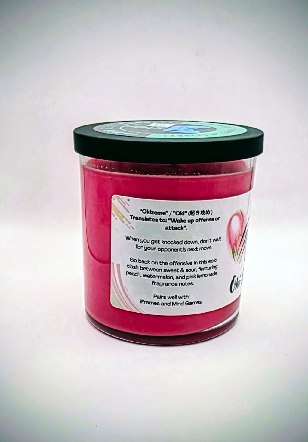 Our Oki-Doki candle in a glass tumbler jar. It has a net weight of 9 oz. and approximately a 40 hour burn time. It features a mixture of sweet and sour fragrance notes including peach, watermelon, and pink lemonade. The clash between sweet and sour is meant to represent the clash between powerful fighters in your favorite fighting game franchises. The label is white with images reminiscent of the fireball and slashing attacks featured in many fighting games.