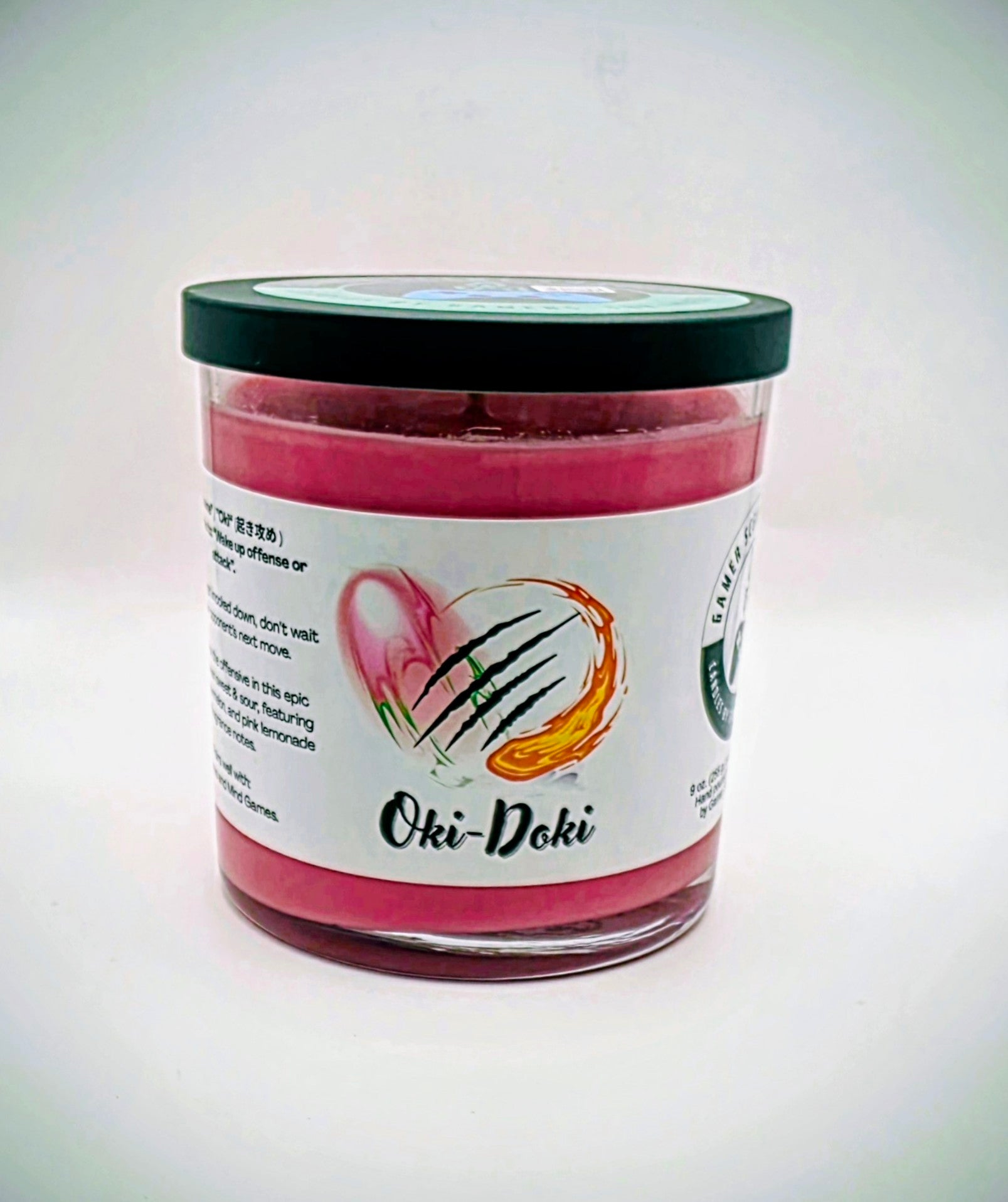 Our Oki-Doki candle in a glass tumbler jar. It has a net weight of 9 oz. and approximately a 40 hour burn time. It features a mixture of sweet and sour fragrance notes including peach, watermelon, and pink lemonade. The clash between sweet and sour is meant to represent the clash between powerful fighters in your favorite fighting game franchises. The label is white with images reminiscent of the fireball and slashing attacks featured in many fighting games.