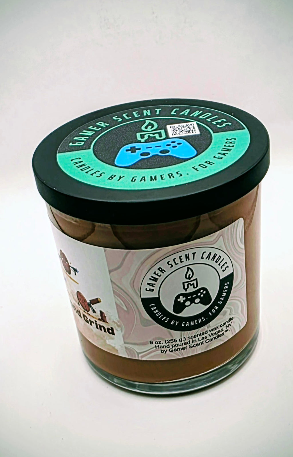 Our "Rise and Grind" fragrance in a 9 oz. glass tumbler jar with black lid. It features bold fragrance notes of fresh brewed coffee infused with salted honey butter. Our 9 oz. jars have approximately a 40 hour burn time. The label features cartoon coffee beans with weapons.