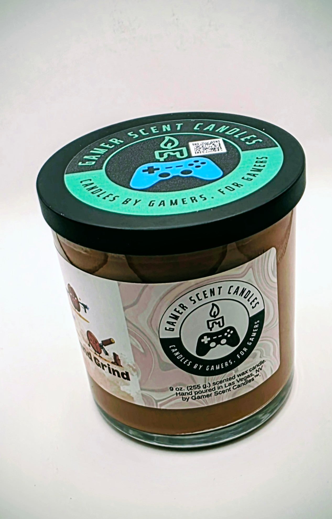 Our "Rise and Grind" fragrance in a 9 oz. glass tumbler jar with black lid. It features bold fragrance notes of fresh brewed coffee infused with salted honey butter. Our 9 oz. jars have approximately a 40 hour burn time. The label features cartoon coffee beans with weapons.