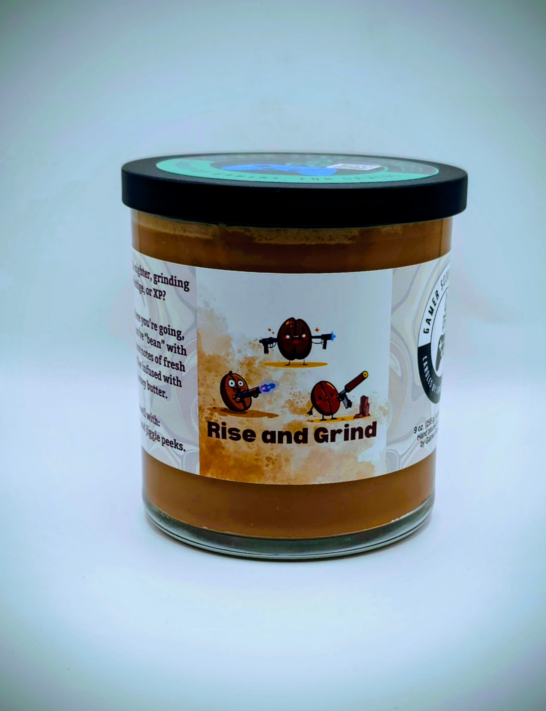 Our "Rise and Grind" fragrance in a 9 oz. glass tumbler jar with black lid. It features bold fragrance notes of fresh brewed coffee infused with salted honey butter. Our 9 oz. jars have approximately a 40 hour burn time. The label features cartoon coffee beans with weapons.