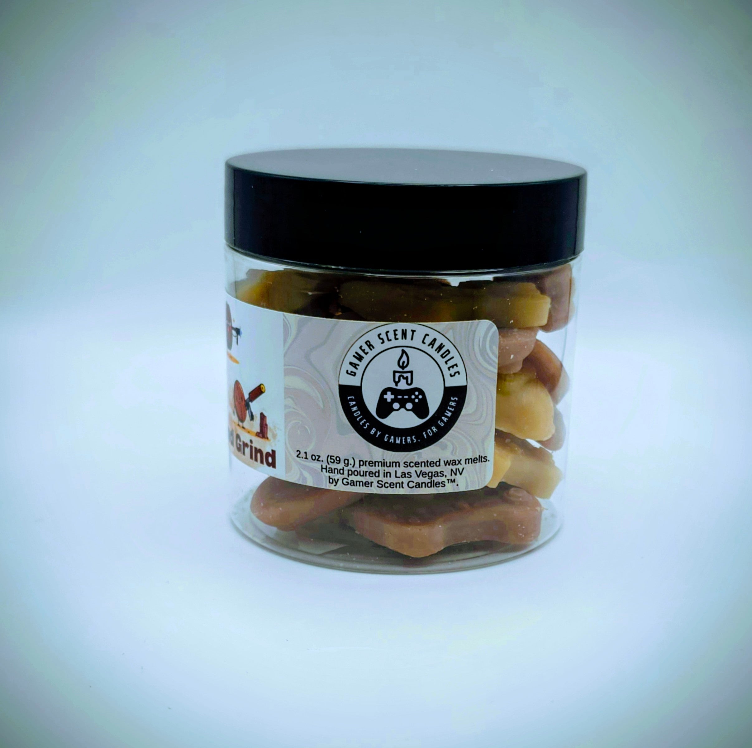 A jar of premium wax melts in an assortment of video game controller shapes. The scent is called "Rise and Grind". The wax melts are a mix of coffee brown and golden cream colors. The label features cartoon coffee beans with weapons.