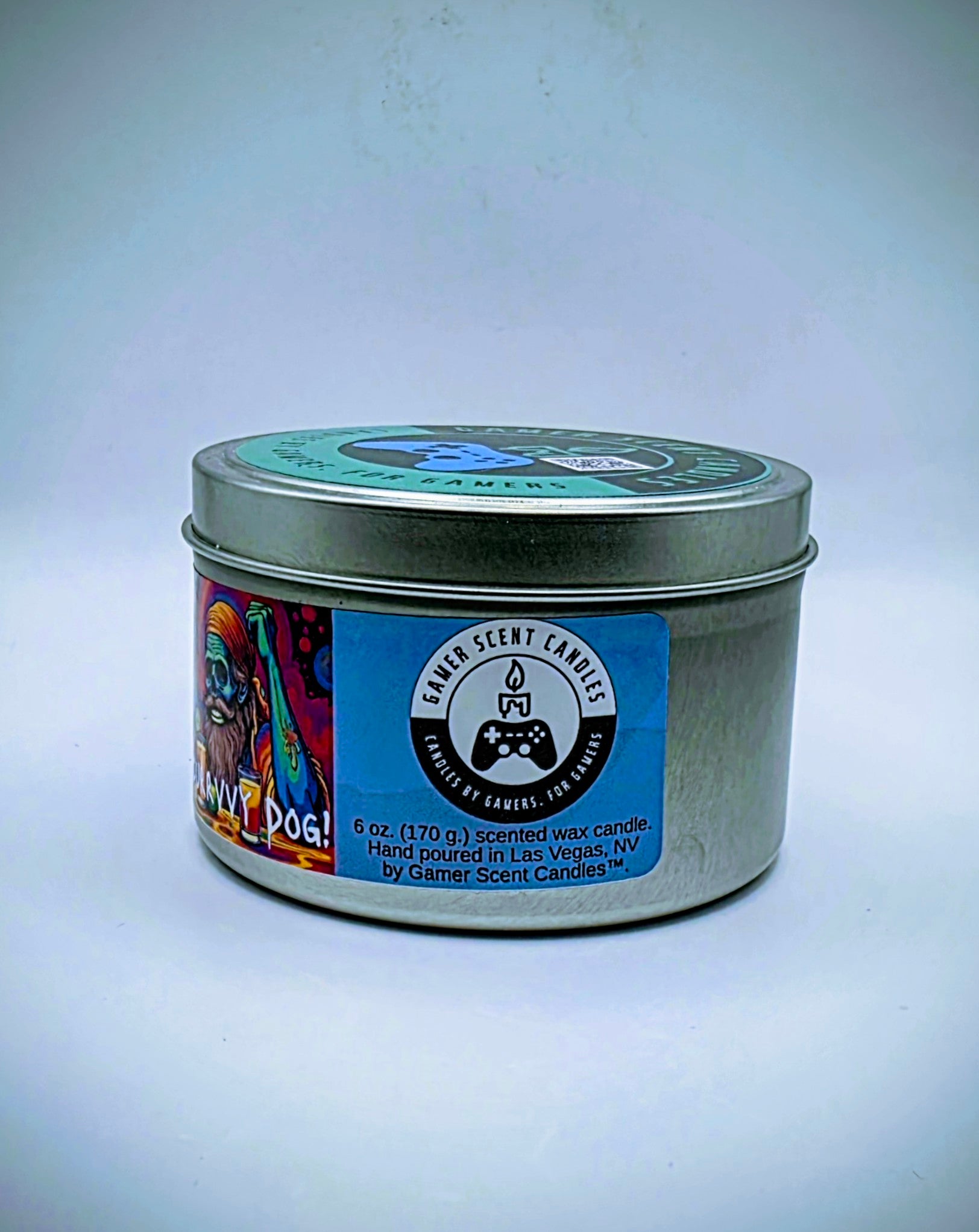 Our "Scurvy Dog" candle in a 6 oz. tin. The candle features spiced coconut and lime fragrance notes. The candle is blue and features a blue label with a psychedelic pirate holding a drink garnished with a lime. Our 6 oz. candles have approximately a 25 hour burn time.