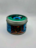Our "Scurvy Dog" candle in a 6 oz. tin. The candle features spiced coconut and lime fragrance notes. The candle is blue and features a blue label with a psychedelic pirate holding a drink garnished with a lime. Our 6 oz. candles have approximately a 25 hour burn time.