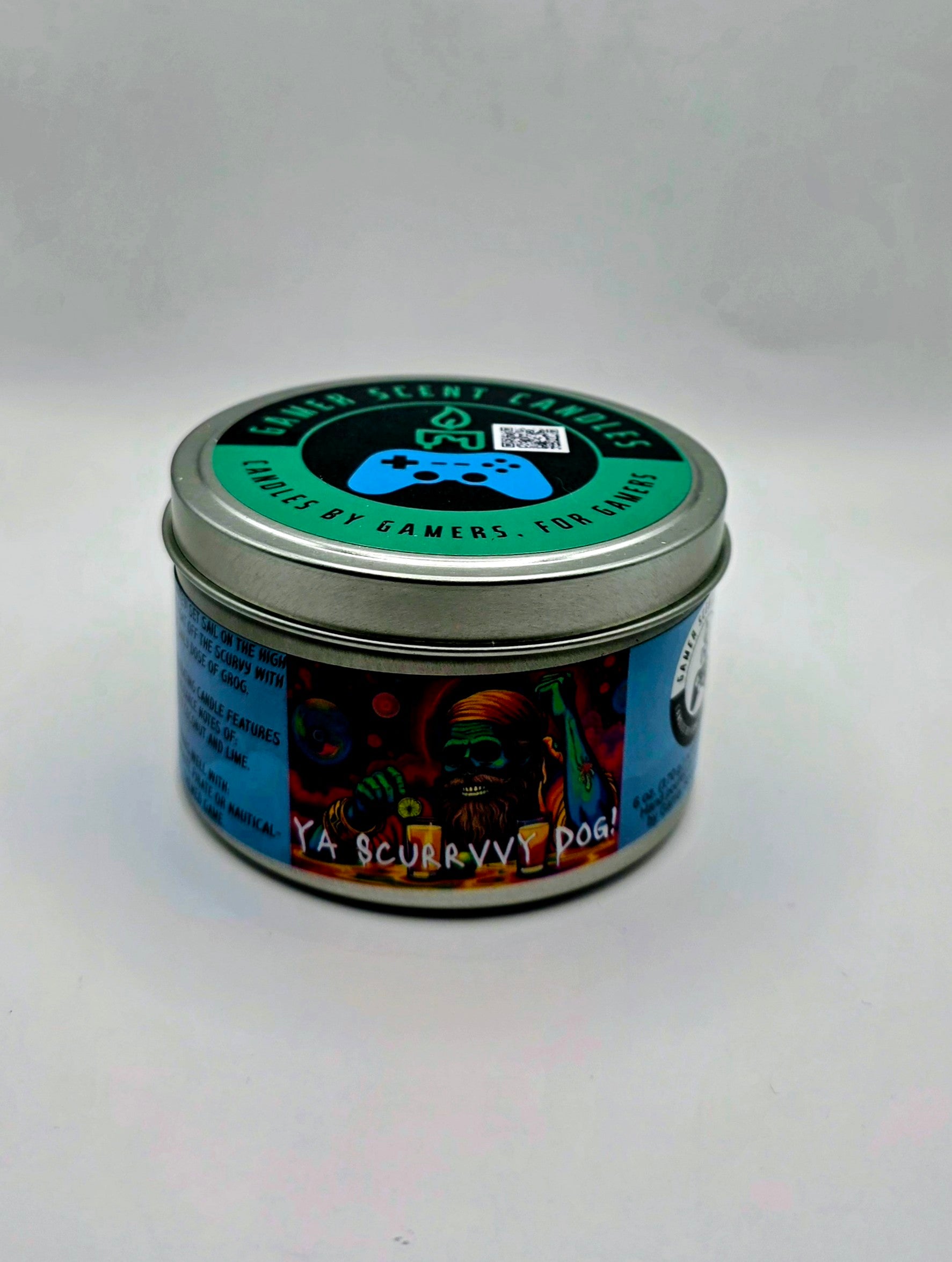 Our "Scurvy Dog" candle in a 6 oz. tin. The candle features spiced coconut and lime fragrance notes. The candle is blue and features a blue label with a psychedelic pirate holding a drink garnished with a lime. Our 6 oz. candles have approximately a 25 hour burn time.