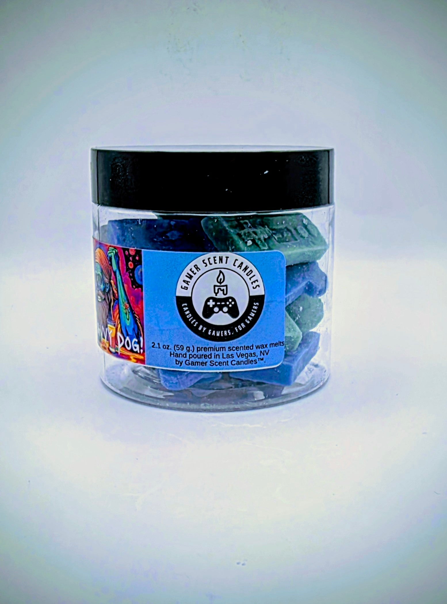A jar of premium wax melts in an assortment of video game controller shapes. The scent is called "Scurvy Dog". The wax melts are a mix of blue and green colors.  The label features a psychedelic pirate skeleton sitting in front of a beverage garnished with lime.